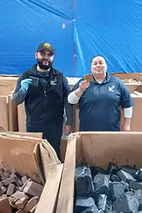 Photo of pallets of soap and two shelter volunteers smiling and holding up bars of soap.